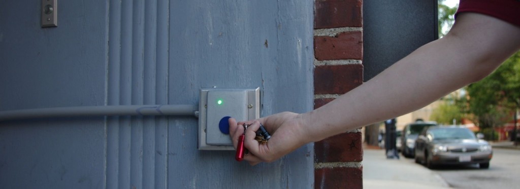 A person uses a key fob on the Ctrl-O access-control reader at a makerspace door.
